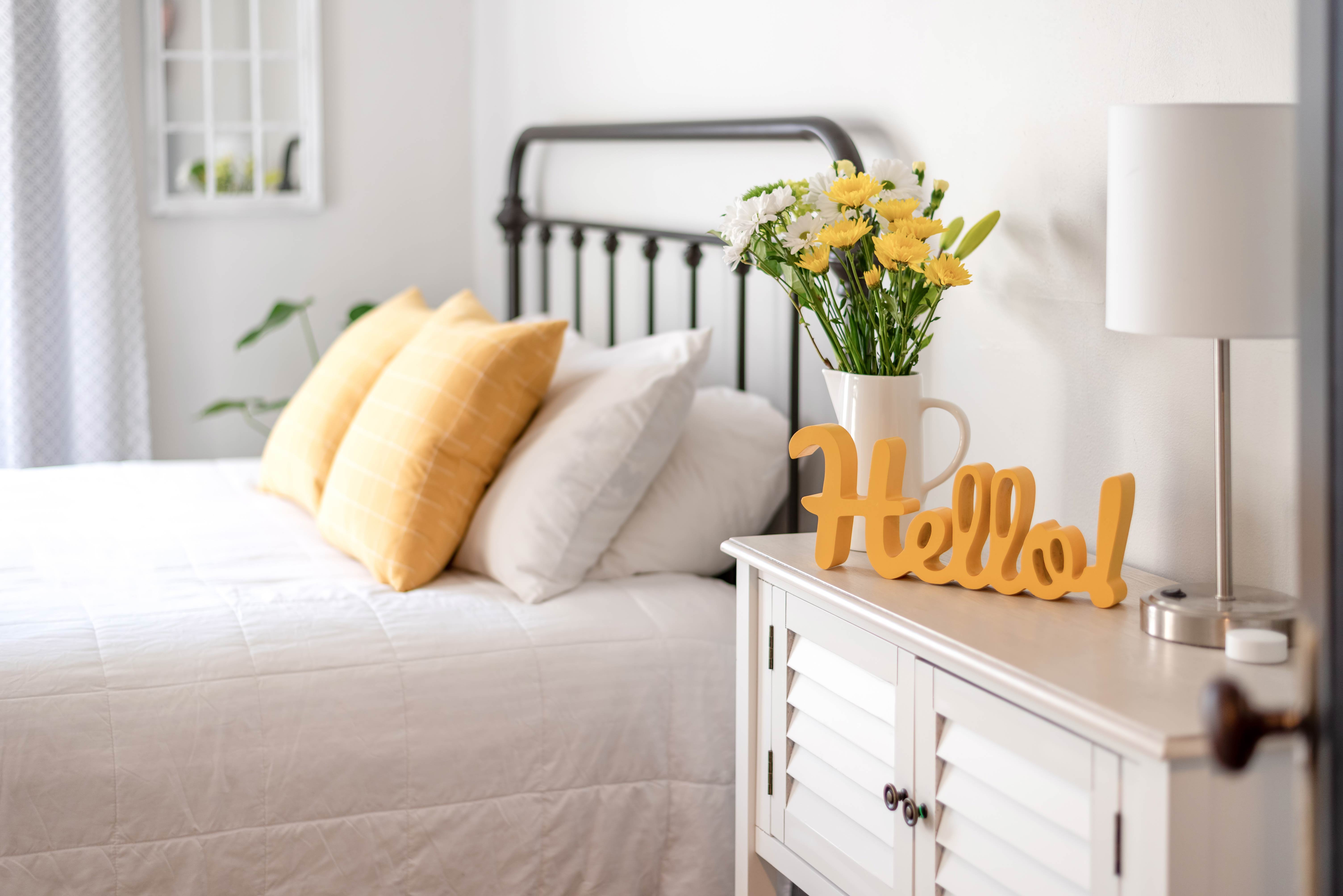 Cheerful hello sign in clean and bright bedroom with yellow accents